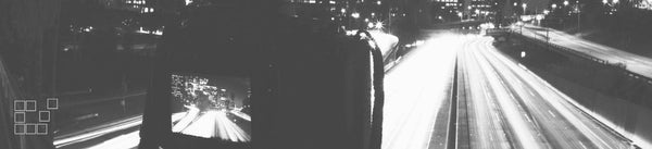 A camera screen in the foreground of a black and white night scene with bright traffic light trails.