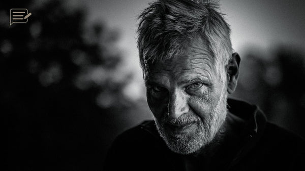 Black and white close-up portrait of a bearded man, with side light revealing his eyes and the texture of his face.