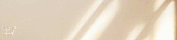 Beige wall art banner with diagonal sunlight across a softly textured neutral surface