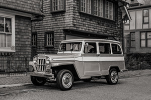 Zweifarbiger Willys Kombi, geparkt neben einer verwitterten Schindelverkleidung