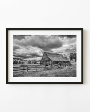 Abandoned barn near Hedley, British Columbia, behind a broken rail fence beneath dark clouds.