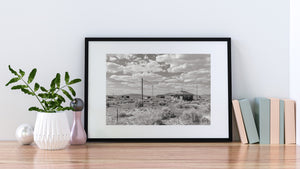 A worn rural building and sagging utility wires in an open Nevada desert landscape.