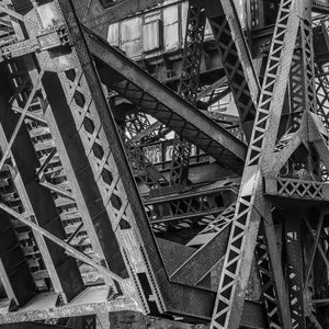 Schwarzweißfoto von überlappenden Stahlstützen auf einer Industriebrücke in Chicago.