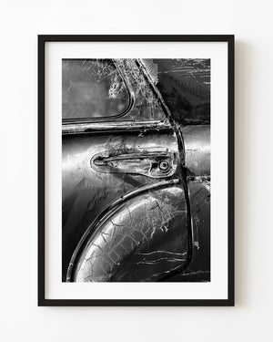 Weathered classic car door with cracked paint and cobwebs, photographed in black and white.