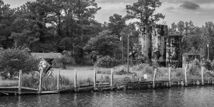 Weathered fuel tanks and crooked dock pilings along a Florida waterfront.