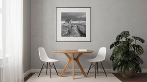 Schwarz-Weiß-Fotografie eines isolierten Hauses mit Satteldach und verwitterten Wänden.