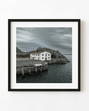Verlassenes weißes Gebäude am Wasser in Mortsund, Norwegen, unter einem bewölkten Küstenhimmel