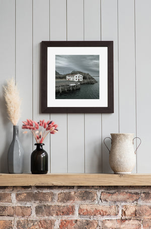 Overcast sky above an abandoned waterfront building and dark coastal water in Norway