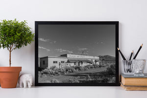 Fotografía en blanco y negro de un edificio abandonado de aguas termales bajo un cielo desértico abierto