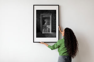 Light catches the worn edges of a wooden frame against dark brick walls