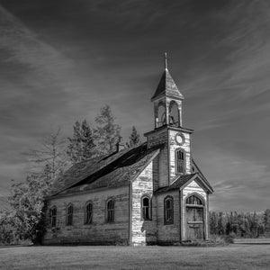 Iglesia de pradera desgastada con revestimiento desconchado y un campanario abierto