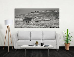 Schwarz-Weiß-Fotografie von abgenutzten Dachlinien und kleinen Gebäuden in einer weiten Landschaft im Südwesten.
