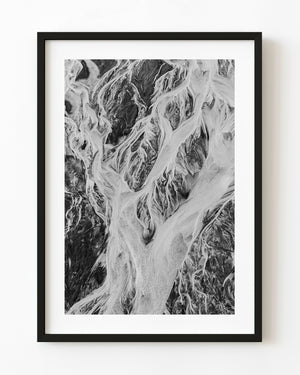 Bright braided channels divide dark textured Alaska coastal ground in black and white.