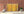 Abstract industrial photograph of riveted metal, worn yellow paint and reddish-brown rust.