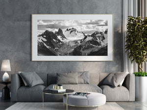 Lingering snow follows mountain ledges above a broad pale glacier.