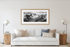 Black and white mountain landscape with textured rock, snowfields and cloud-covered summits.