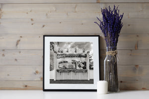 Fotografía mural monocroma de la Ruta 66 con postes de madera, celosías y una escena de una estación de servicio pintada.