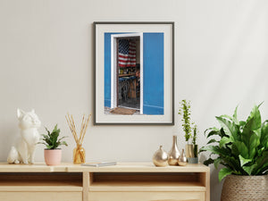 Flag folds and shadowed furnishings appear within a tall narrow opening in a blue wall.