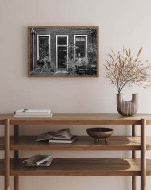 Photographie en noir et blanc d’une maison hollandaise entourée de verdure