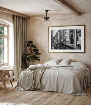 Small surface ripples soften reflected windows beneath a close row of Amsterdam houses.