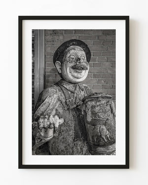 Weathered Amsterdam pub figure with a beer stein photographed in black and white.