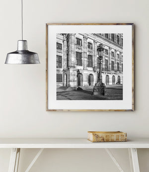 Morgenlicht auf Palastfenstern und geschnitztem Stein hinter einer hohen Amsterdamer Straßenlaterne.