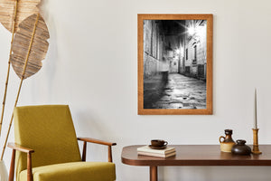 A pale blurred figure contrasts with sharp doorways, windows and stone blocks in the laneway.