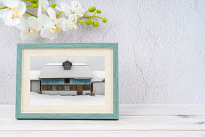 Front view of a blue Ontario barn with a central dormer and snowy roof.