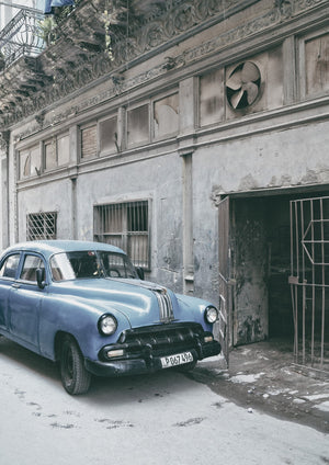 Vertikales Farbfoto eines klassischen Pontiac unter einer abgenutzten Havanna-Fassade.