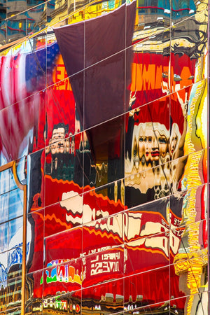 Red, yellow and blue Broadway signs distort across reflective building panels.