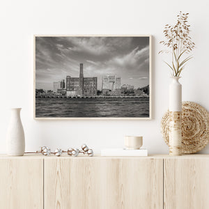 Strukturiertes Wasser und dramatische Wolken umrahmen ein Industriedenkmal am Ufer von Brooklyn.