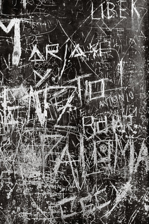 Letras rayadas y graffiti superpuestos cubren una pared oscura de Buenos Aires.