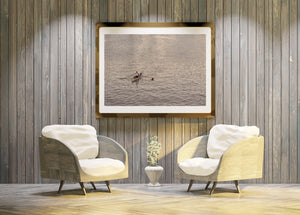 Colour photograph of a lone rower amid gently shimmering evening water.