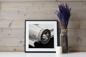 Light glints across polished chrome and pale bodywork on a classic Cadillac.