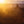 A sandstone butte rises from dark canyon terrain beneath a warm glowing sunset.
