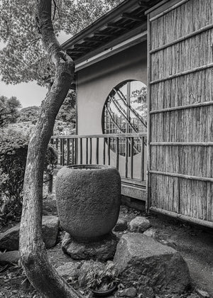 Traditional Japanese garden architecture with a round window beside a textured wooden exterior.