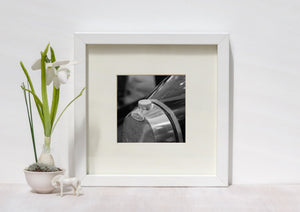 Classic automotive photograph showing the Bugatti emblem beside reflective metal and a dark bonnet.