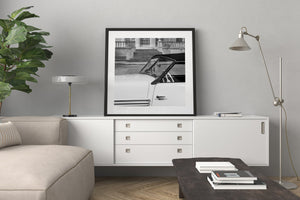 Reflective metal trim traces the windshield and pale body panels of a historic Cord roadster.