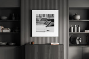Square monochrome photograph of a Cord roadster cabin and door against grand architectural windows.