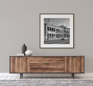 Repeating columns and shadowed archways frame a Cuban street scene in black and white.