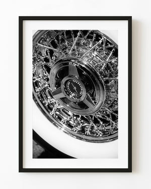 Black and white close-up of a classic Thunderbird wire wheel with polished chrome spokes and a broad whitewall tyre.