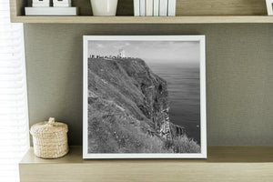 Grassy coastal slopes descend toward the sea below the Cliffs of Moher’s small tower.