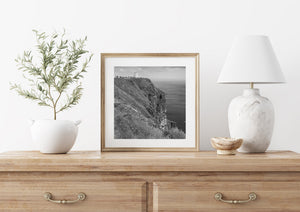 A small tower and distant visitors give scale to Ireland’s steep Atlantic cliffs.