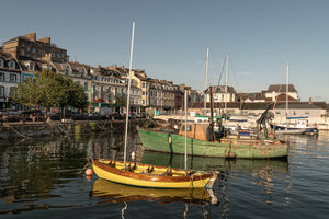 A yellow boat floats in calm Cobh Harbour beneath a pale evening sky.