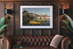 Golden light illuminates moored vessels and colourful houses along Cobh Harbour.