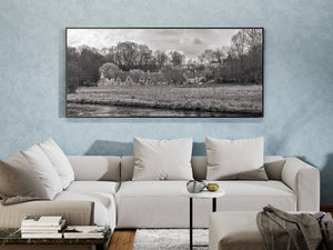 Dark river water contrasts with pale grass and textured cottages in a Cotswolds village.