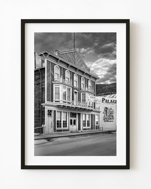 The Palace Grand Theatre in Dawson City stands beneath textured clouds in black and white.