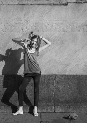Barefoot girl and her sharp shadow on a Buenos Aires stone wall, monochrome street photograph.