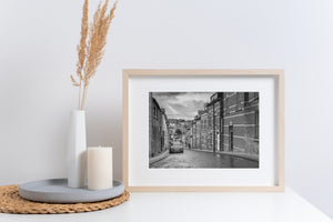 Receding windows and brick walls above a wet sloping street in Derry.