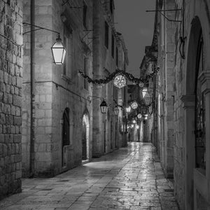 Callejón tranquilo de Dubrovnik con luces colgantes y edificios de piedra desgastados